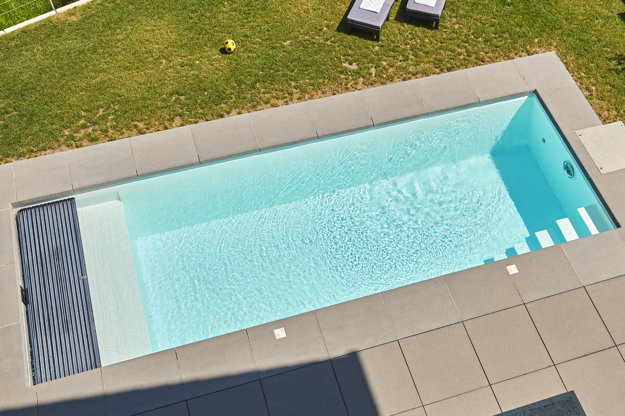 Zwembad met ligbank en zonne-rolluikafdekking in wit